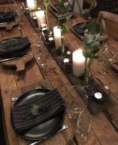 a wooden table topped with plates and candles