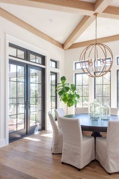 a dining room table with white chairs and a chandelier hanging from the ceiling