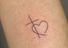 a small heart tattoo on the back of a woman's arm with a cross in it