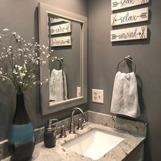 a bathroom sink sitting under a mirror next to a blue vase with flowers in it