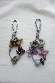 two key chains with charms attached to them on a white cloth covered surface in the shape of flowers