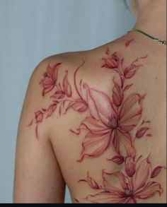 the back of a woman's shoulder with red flowers on it and green leaves