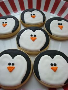 six decorated penguin cookies sitting on top of a plate