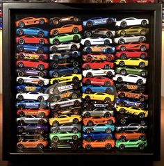 a display case filled with lots of different colored toy cars on top of a wooden table