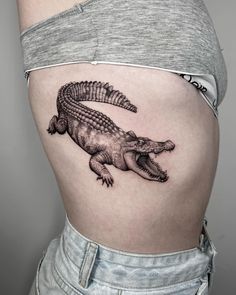 a woman's stomach with an alligator tattoo on it