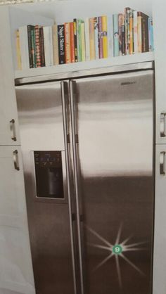 a stainless steel refrigerator with bookshelves above it