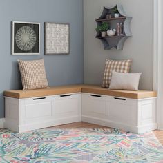 a corner bench with storage underneath it in a room that has blue walls and wooden flooring