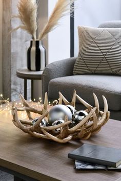 a wooden table topped with antlers and ornaments on top of it next to a couch