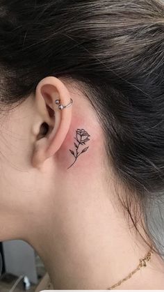 a woman's ear with a small rose tattoo on it