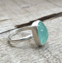 A stunning light aqua blue chalcedony has been set in sterling silver with a handmade ring band from sterling silver half dome wire. The cushion cut rectangle stone is 14mm x 10mm in size. The faceted cut of the stone gives the ring a geometric look that also helps catch the light and sparkle. This stone is a light blue as pictured but certain light can bring out a green hue to the stone. Made to order! Chalcedony is the horoscope stone for cancers, June and July birthdays. The video features th Turquoise Chalcedony Ring Jewelry, Turquoise Chalcedony Gemstone Rings, Boho Rocker, Rectangle Cushion, Chalcedony Ring, Statement Ring Silver, Ring Boho, Boho Ring, Blue Chalcedony