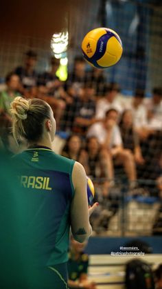 a woman is playing volleyball in front of a large group of people on the bleachers