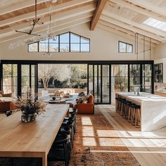 an open kitchen and living room with large windows on the ceiling, dining table in foreground