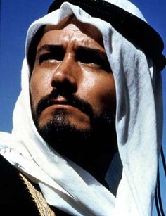 a man wearing a white head scarf and looking off into the distance with his eyes closed