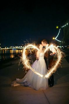 a bride and groom holding sparklers in the shape of a heart