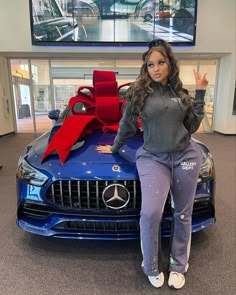 a woman sitting on the hood of a blue car