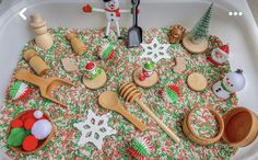 an assortment of wooden spoons and utensils in a white tray with christmas decorations