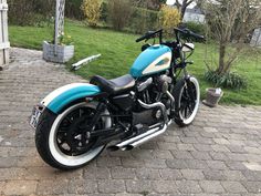 a blue and white motorcycle parked on top of a brick road next to a green field