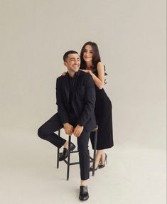 a man and woman sitting on a chair posing for the camera with their arms around each other