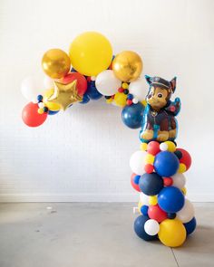 a balloon arch is decorated with balloons and a teddy bear in a pirate hat on top