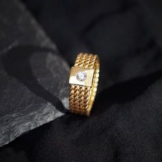 a gold ring with a diamond in the center on a black cloth, close - up