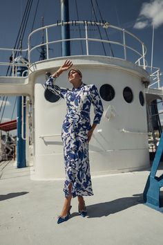 a woman in a blue and white dress standing on the deck of a large boat