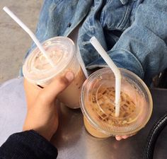 two people sitting at a table with drinks in plastic cups on top of each other