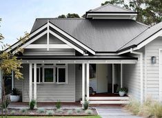 a gray house with white trim on the front door and porch, along with grass