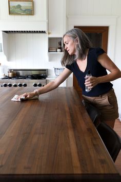 a woman standing at a kitchen counter with her hand on the edge of the table