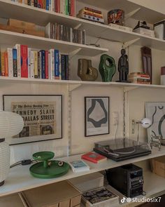 there are many books on the shelves above the desk and below it is a record player