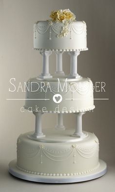 a three tiered white wedding cake with flowers on top