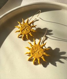 two yellow sun earrings sitting on top of a white plate