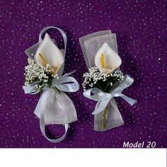 two boutonnieres with white flowers and baby's breath