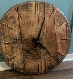 a clock made out of wooden planks sitting on the floor next to a wall