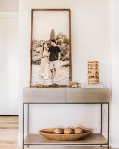 a wooden bowl sitting on top of a table next to a shelf with pictures above it