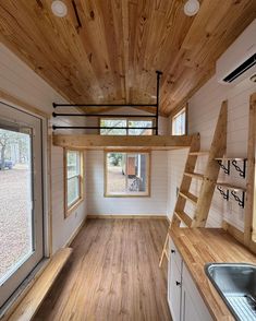 the interior of a tiny house with wood flooring and ladders on the ceiling