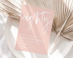 a pink and white birthday card with the word eighty on it next to a fan