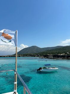 a boat is in the water near a flag on a pole and some people are swimming