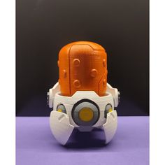 an orange and white robot head sitting on top of a purple surface