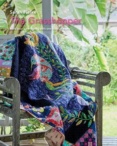 a quilted blanket sitting on top of a wooden bench