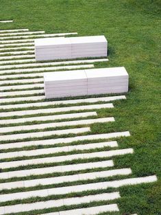 several white benches sitting on top of grass covered ground