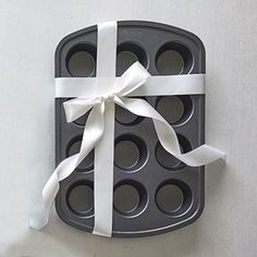 a muffin tin with a white ribbon tied around it