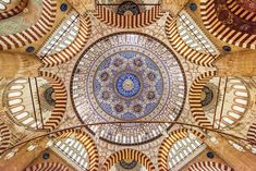 an ornate ceiling in the middle of a building with lots of windows and designs on it