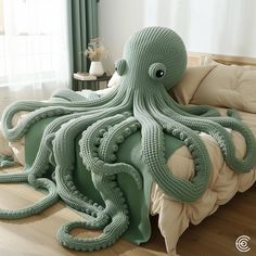 an octopus made out of knitted material sitting on a bed with pillows and blankets