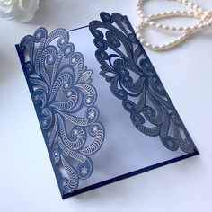 a card with an intricate design on it next to a pearl necklace and white flowers