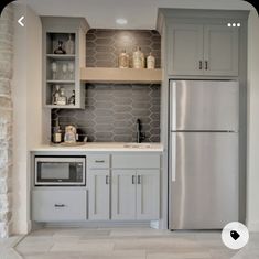 a kitchen with gray cabinets and white tile flooring is shown in this image, there are shelves above the refrigerator