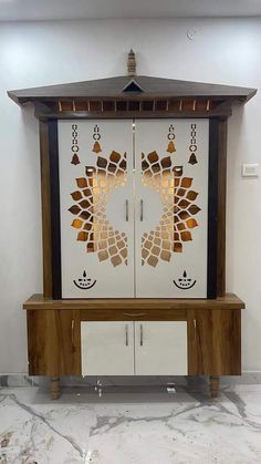 a white cabinet with two doors and an intricate design on the front, sitting in a room