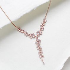 Our breath-taking rose gold bridal Y necklace is perfect for your special day. The necklace features a unique Y-shaped design, with an eye-catching array of small stones, making it a must-have for any bride. Its timeless design is perfect for creating lasting memories. - Created with Premium Cubic Zirconia stones - Available in rose gold, yellow gold, and rhodium finish. - Necklace pictured measures 16 inches and extends to 18 inches  - Decorative vine portion measures 4 inches, drop in center i Rose Gold Delicate Bridal Necklace For Formal Occasions, Delicate Rose Gold Bridal Necklace For Formal Occasions, Rose Gold Wedding Necklace With Elegant Design, Rose Gold Necklace With Adjustable Chain For Wedding, Rose Gold Necklaces With Adjustable Chain For Wedding, Dainty Rose Gold Bridal Necklace For Anniversary, Rose Gold Lariat Jewelry For Wedding, Delicate Rose Gold Bridal Necklace For Party, Rose Gold Lariat Necklace For Wedding With Adjustable Chain