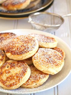 some pancakes are on a plate with sugar sprinkled on them and another plate is in the background