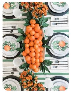 the table is set with oranges and white plates, black and green placemats