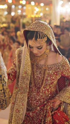 a woman in a red and gold bridal gown is walking down the aisle with other people